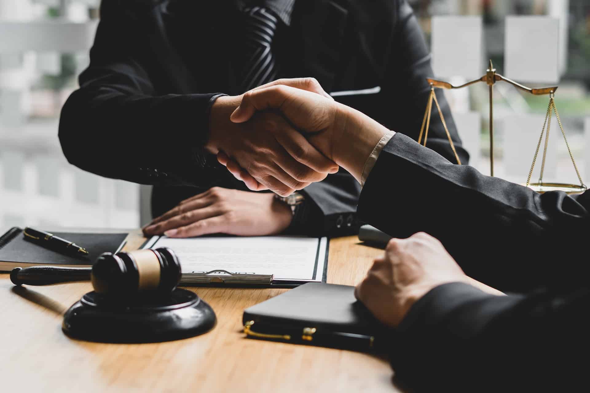 Two Colleagues Shaking Hands Over A Desk | Law Offices Of David M. Wallin